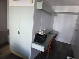A compact kitchen with a built-in microwave, a sink, and a small dining area with chairs.