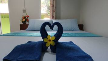 Una habitación de hotel con una cama, una toalla dispuesta en forma de corazón y una decoración floral.
