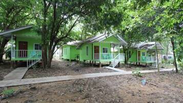 A row of green cabins with wooden decks, surrounded by trees.