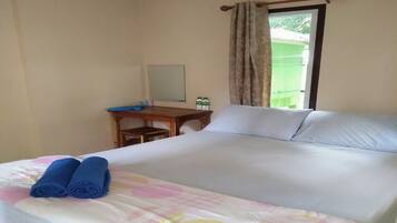 A hotel room with a bed, a desk, and a window with curtains.