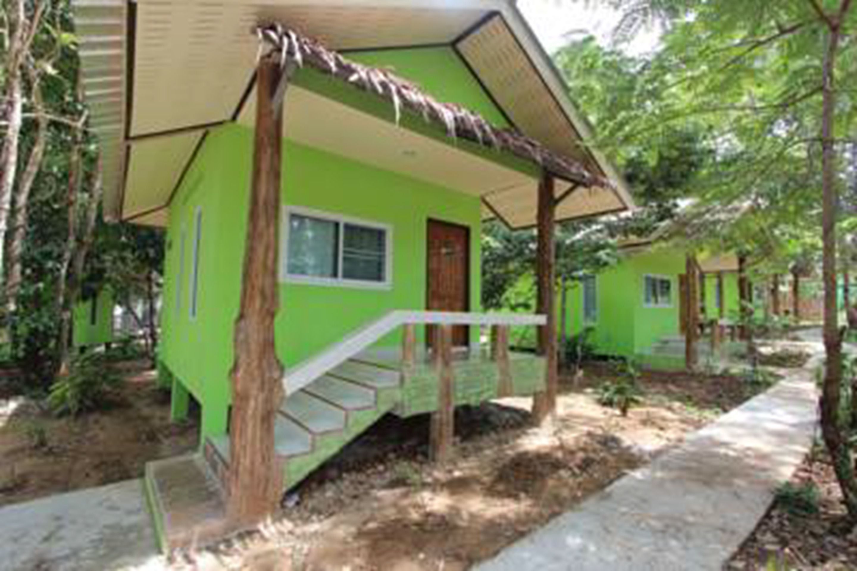 Un petit bâtiment d’un seul étage, à l’extérieur vert et doté d’un toit de chaume.