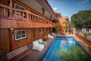 A wooden building with a pool, outdoor seating, and a balcony. - Viking Resort (Pattaya)