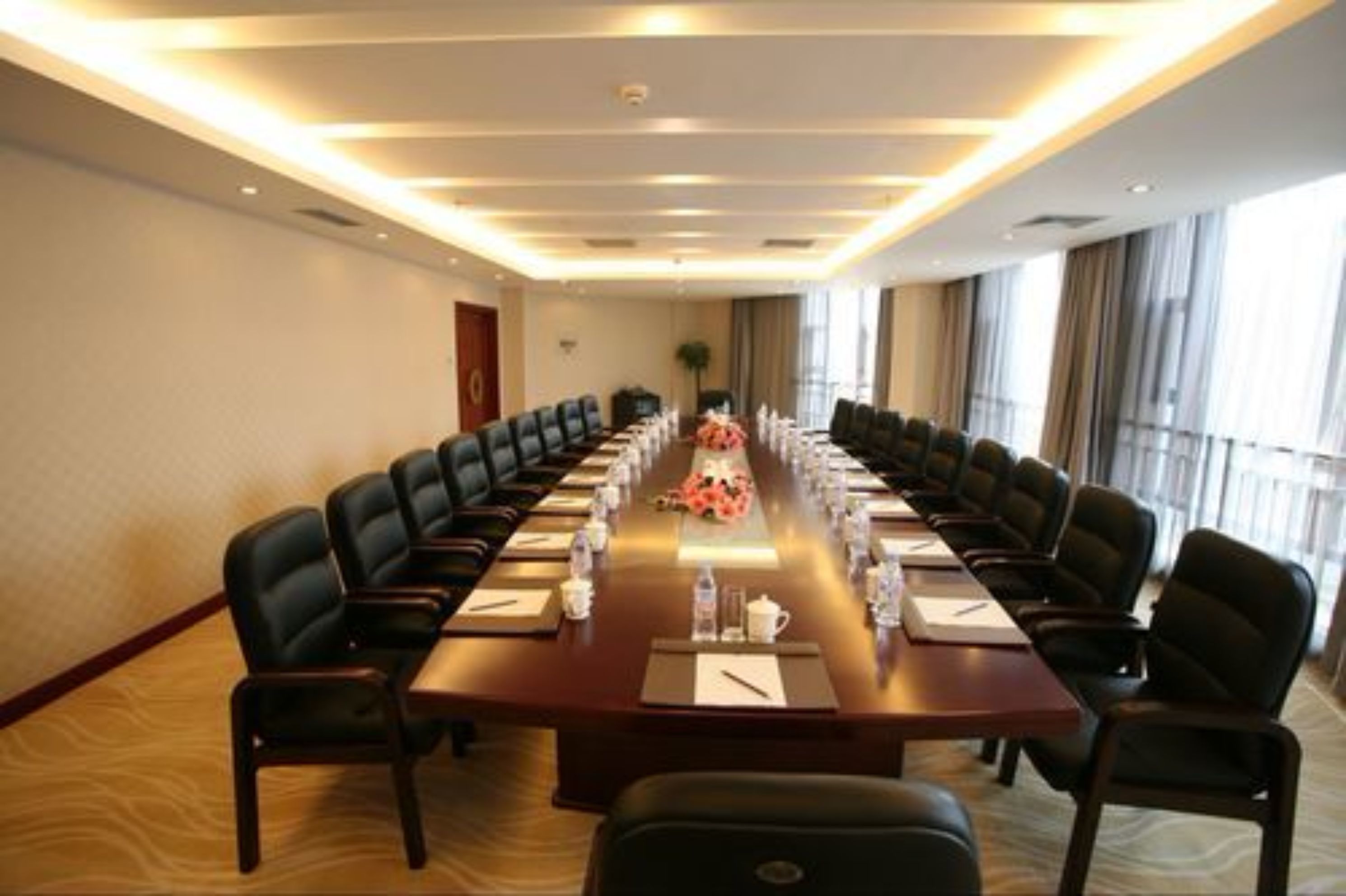 A conference room with a long table, multiple chairs, and a floral centerpiece.
