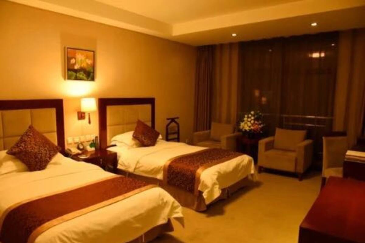 Een hotelkamer met twee bedden, een bureau, een stoel en een groot raam met gordijnen.