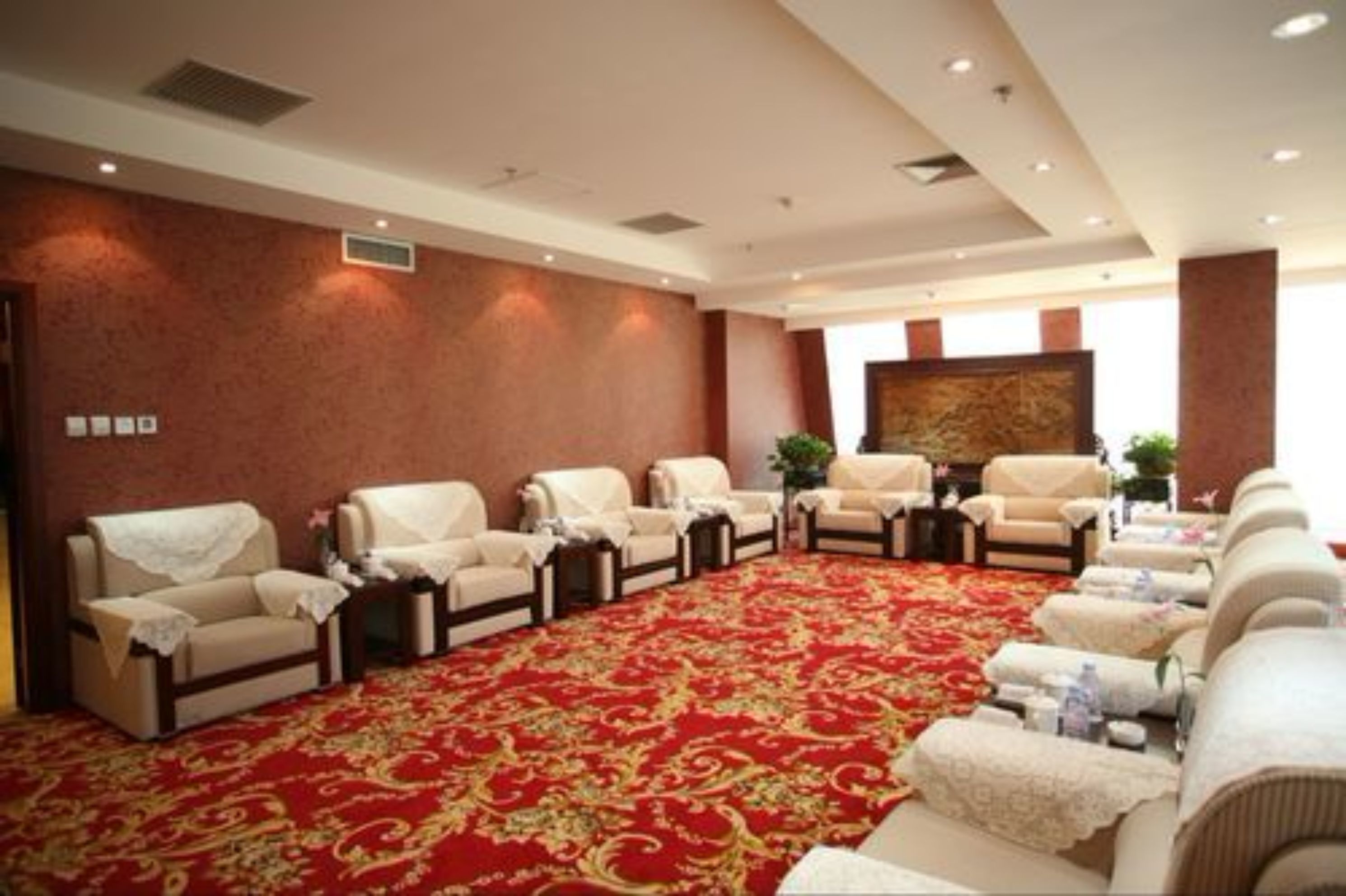 A spacious room with a red carpet, multiple sofas, and a large painting on the wall.