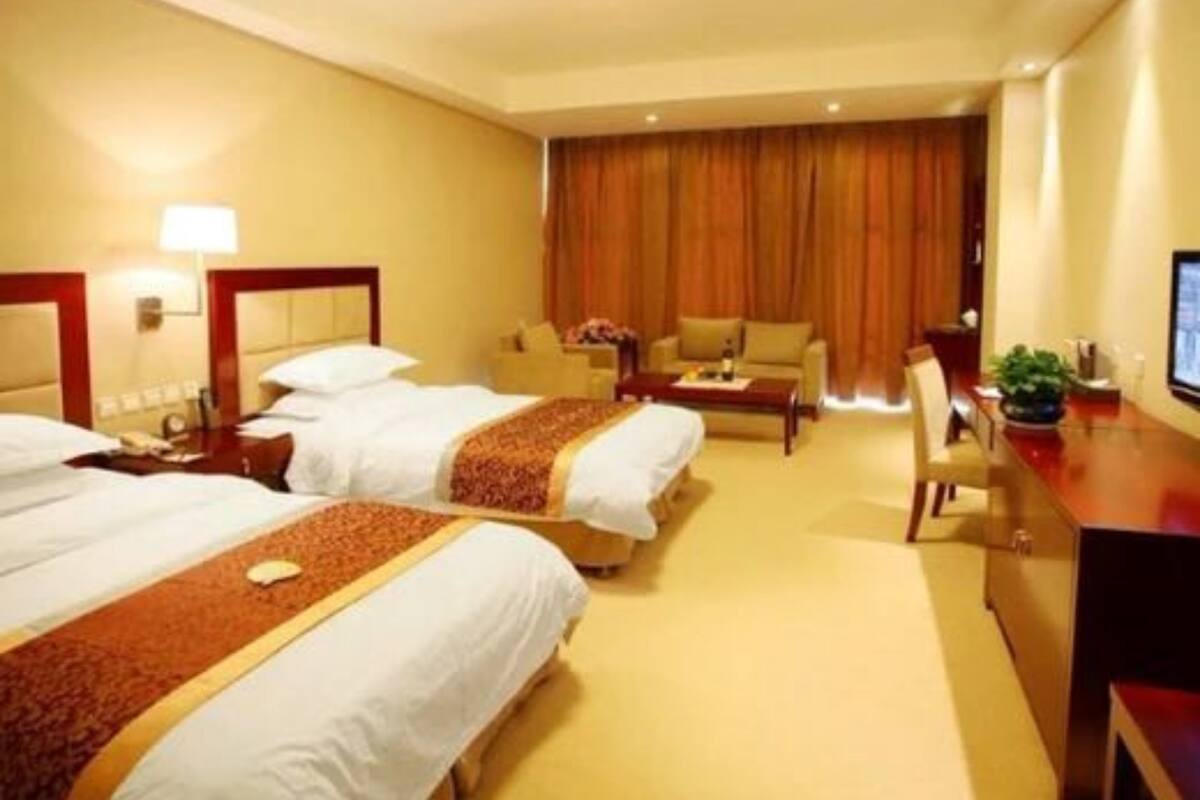 Hotelkamer met twee bedden, een bureau, een stoel, een televisie en een raam met gordijnen.