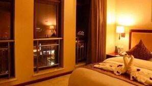 A hotel room with a bed, a nightstand, a window with a view of the city, and a balcony with a railing. - Huashan Mountain International Hotel (Xi'an)