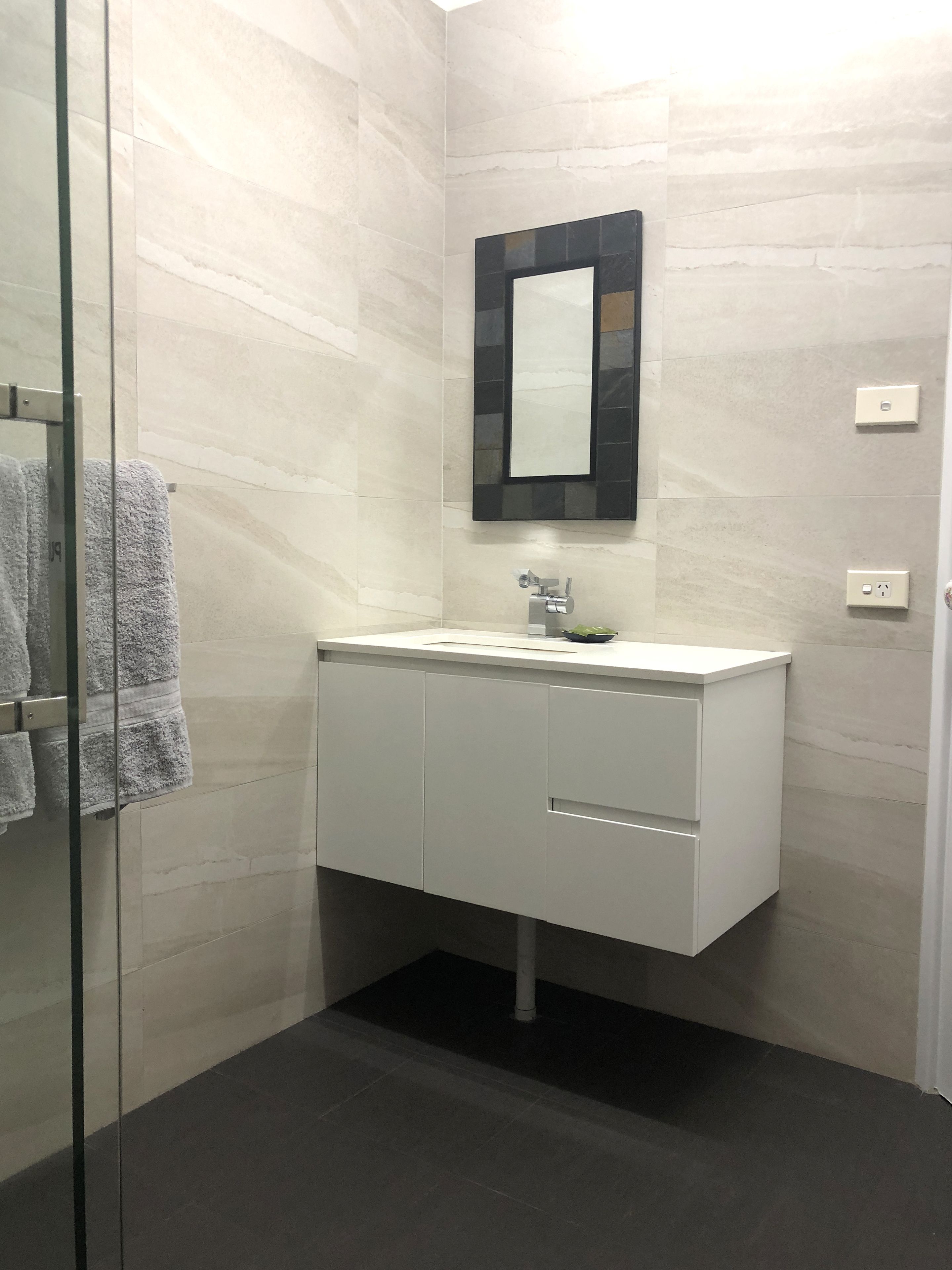 A modern bathroom with a white vanity, a mirror, and a glass shower enclosure.