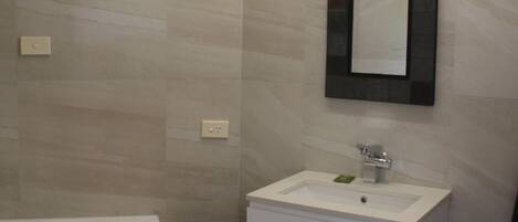 A modern bathroom with a freestanding bathtub, a white sink, and a mirror with a black frame.