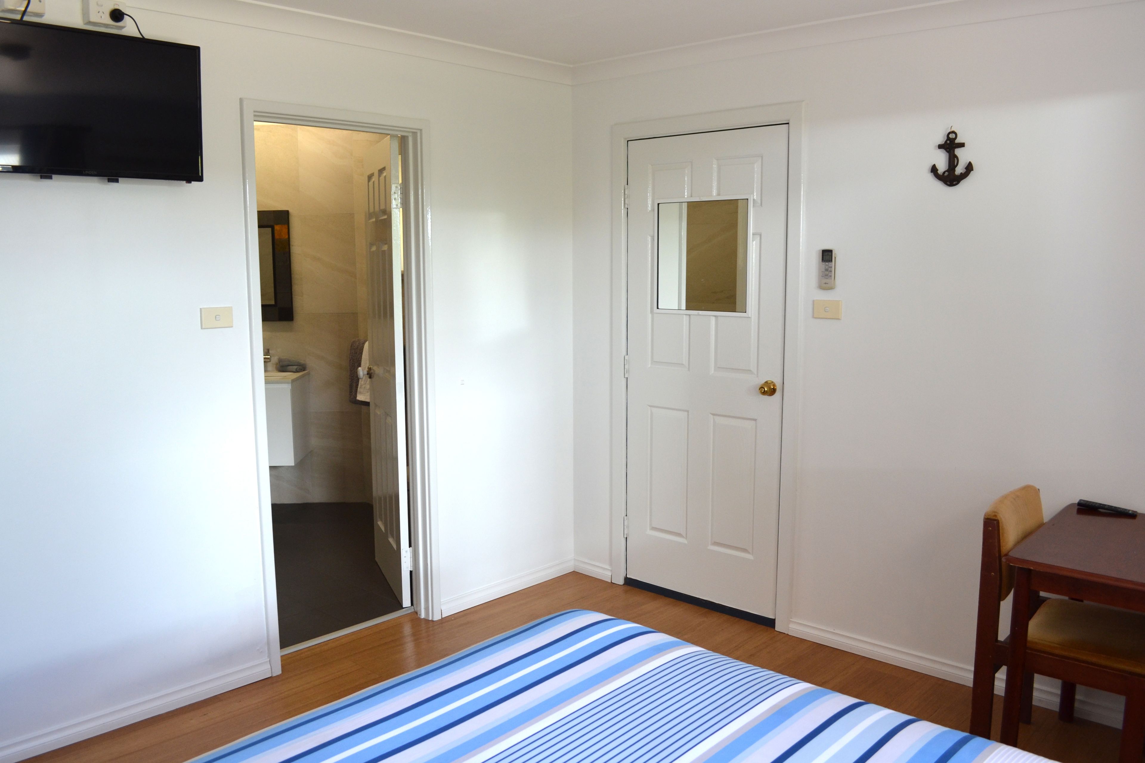 Una habitación con una cama, una puerta, una mesita y una silla.
