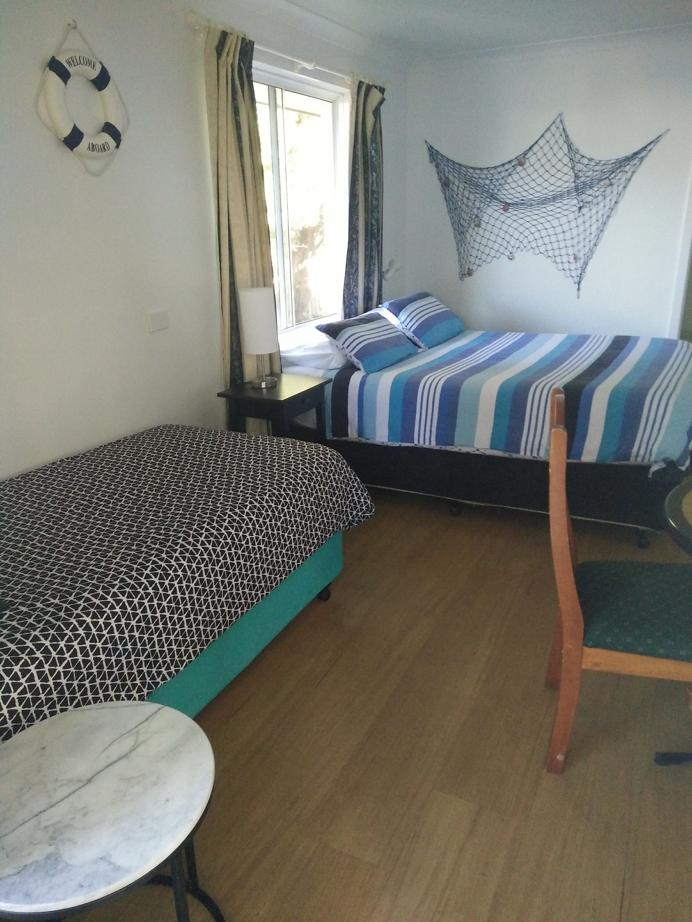 Una habitación con dos camas, una mesita y una silla.