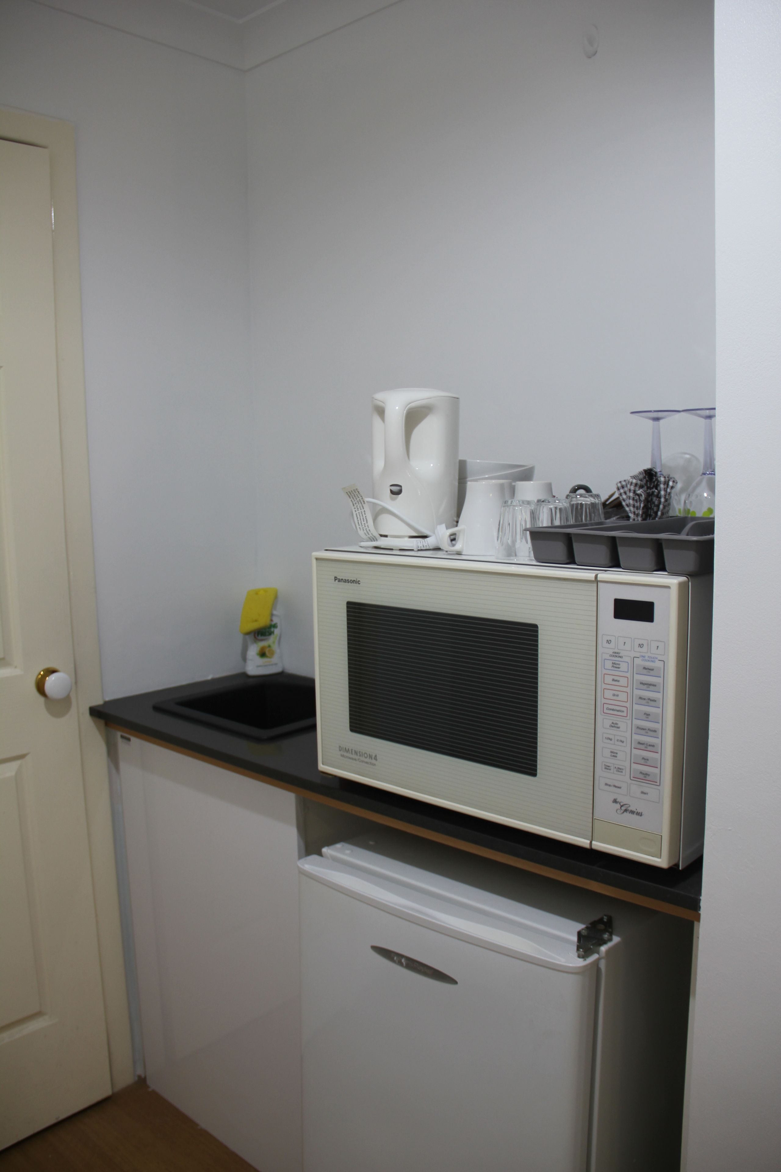 A compact kitchenette with a microwave, coffee maker, and small refrigerator.