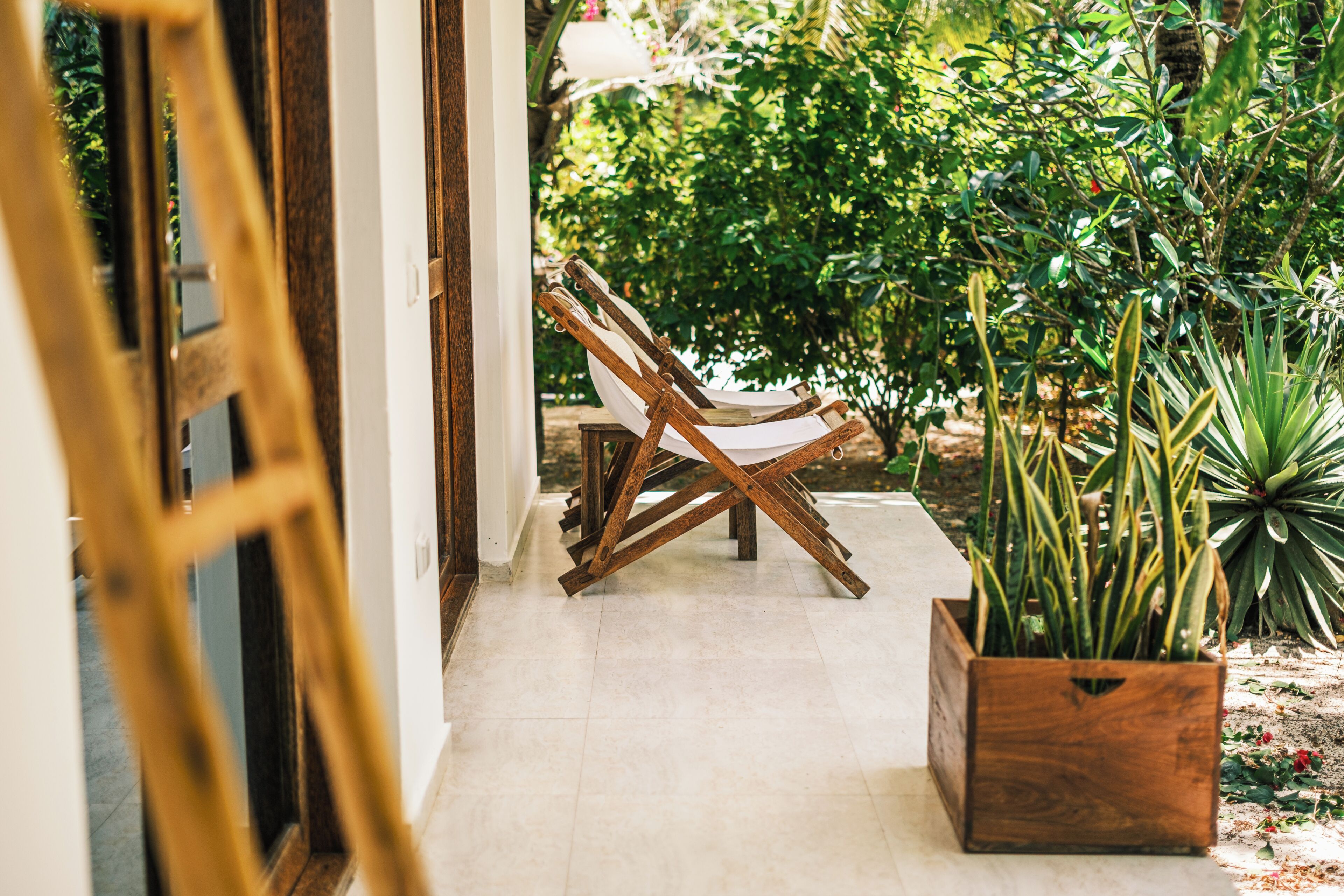 A wooden chair in a tiled area with a potted plant nearby.