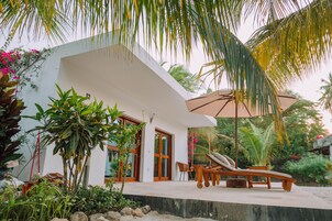 Una casa moderna con fachada blanca, amplios ventanales y un espacio lounge de madera con una tumbona.