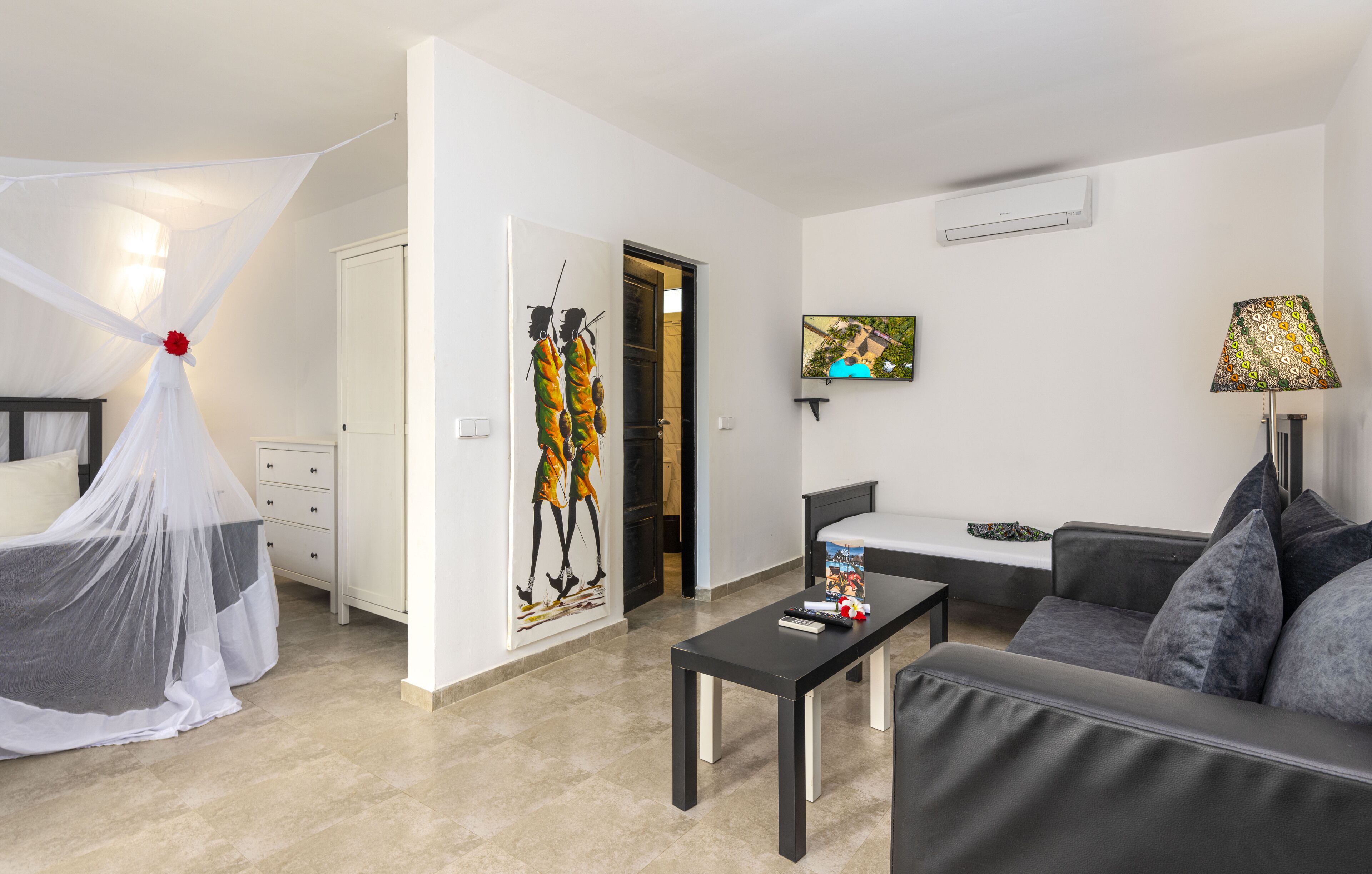 Una habitación de hotel moderna con cama, sofá, mesa de centro y televisión.