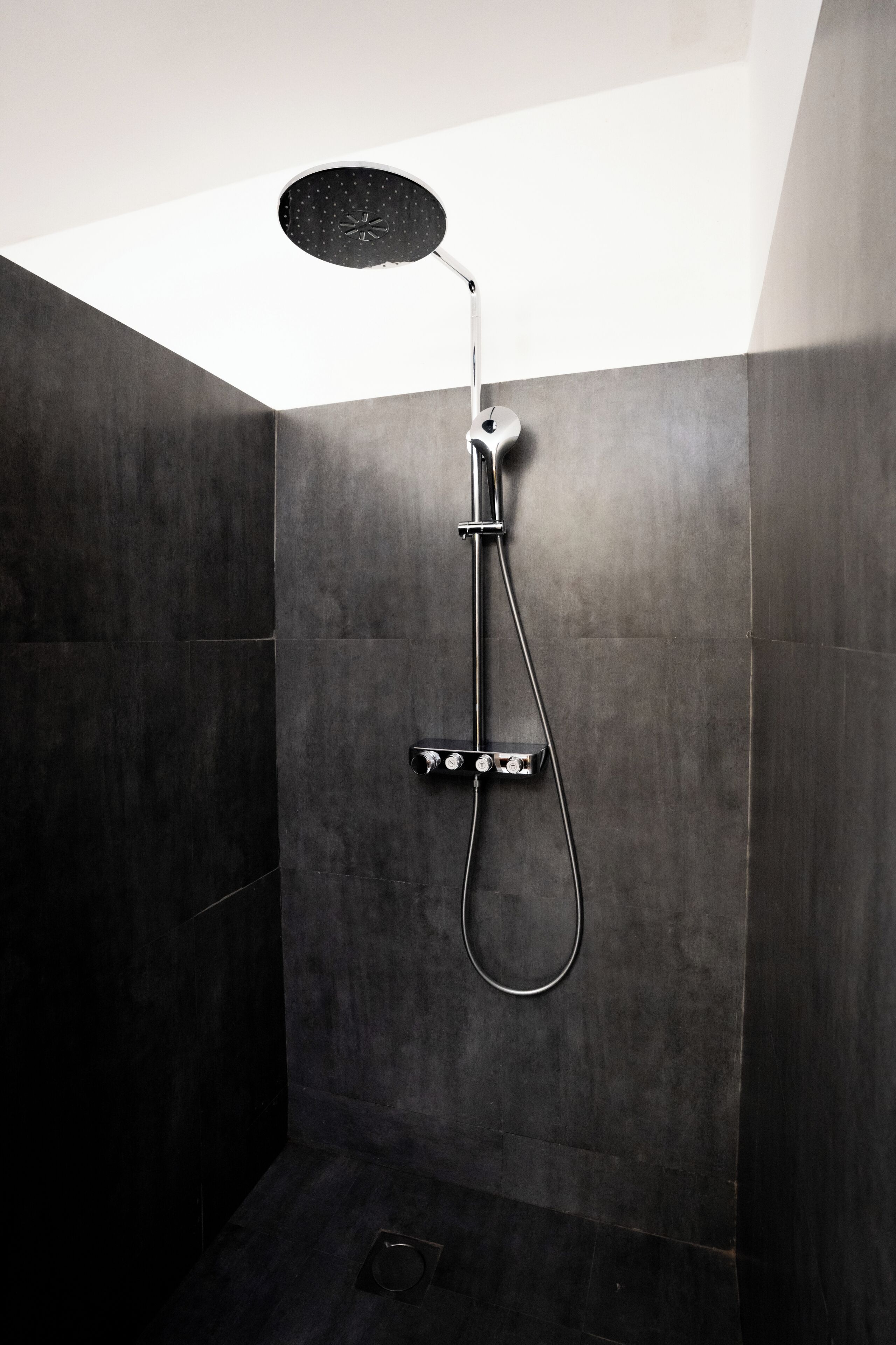 A modern shower with a handheld showerhead and a wall-mounted control panel.