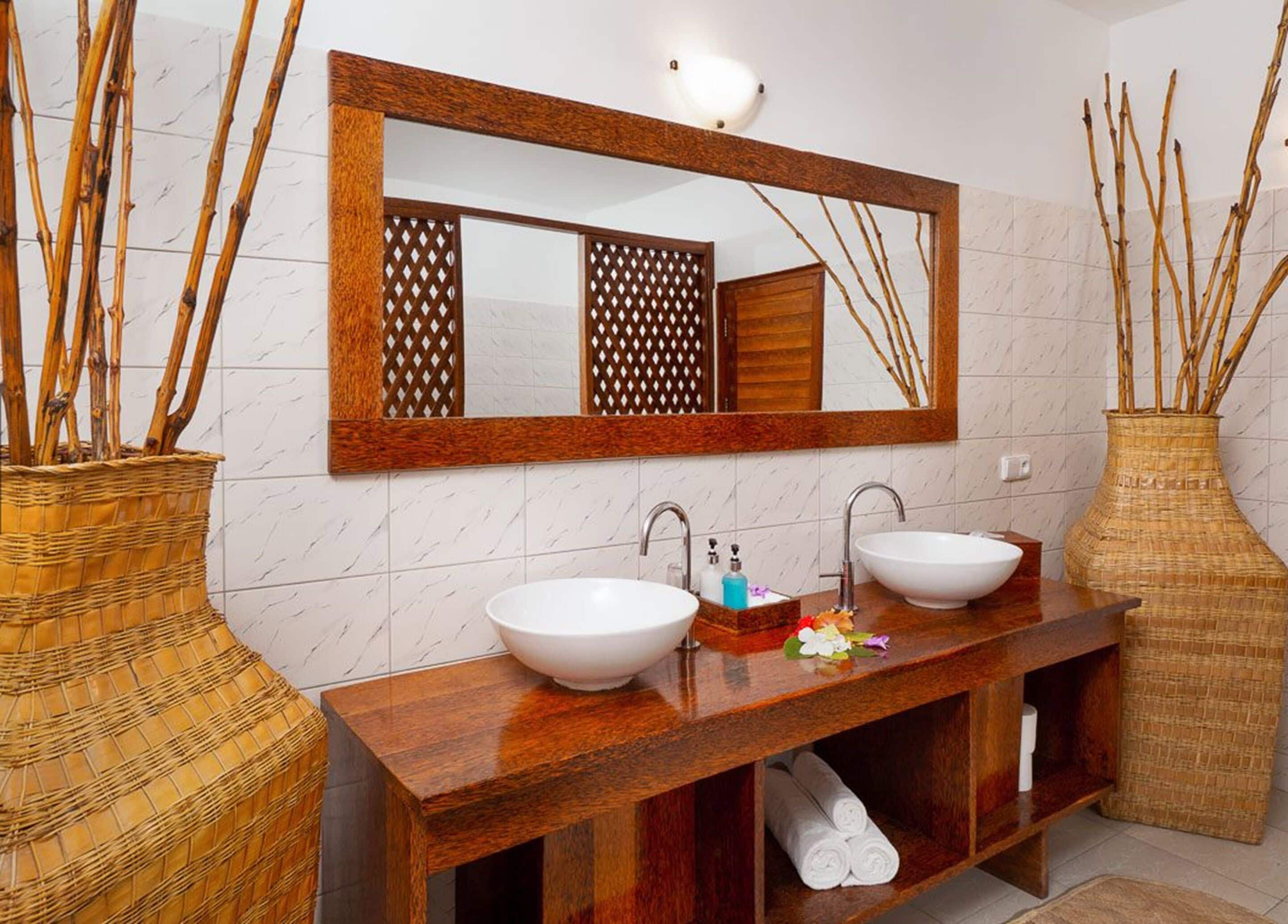 A bathroom with two sinks, a large mirror, and decorative vases.