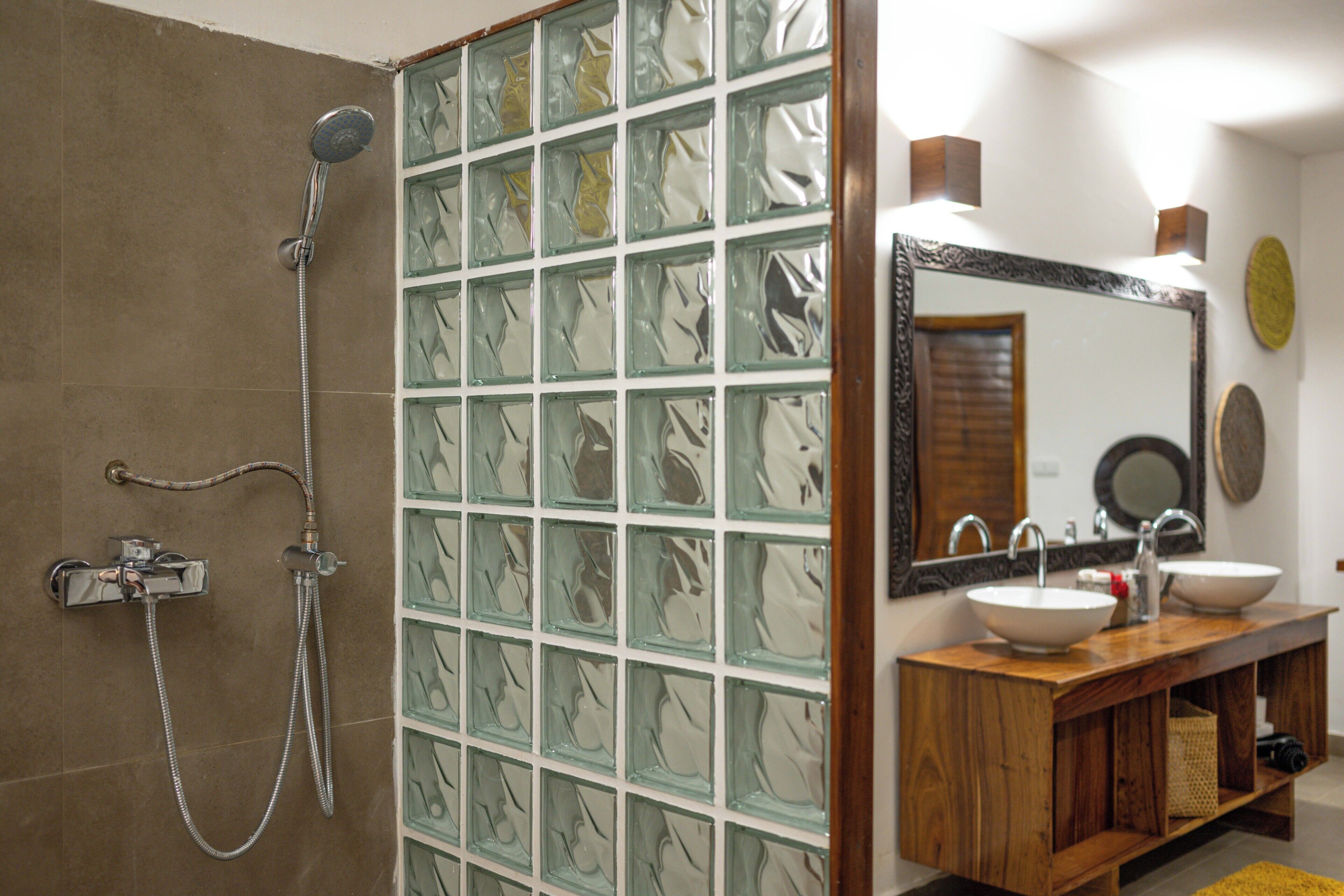 A bathroom with a glass shower enclosure, a wooden vanity with a mirror, and a sink.