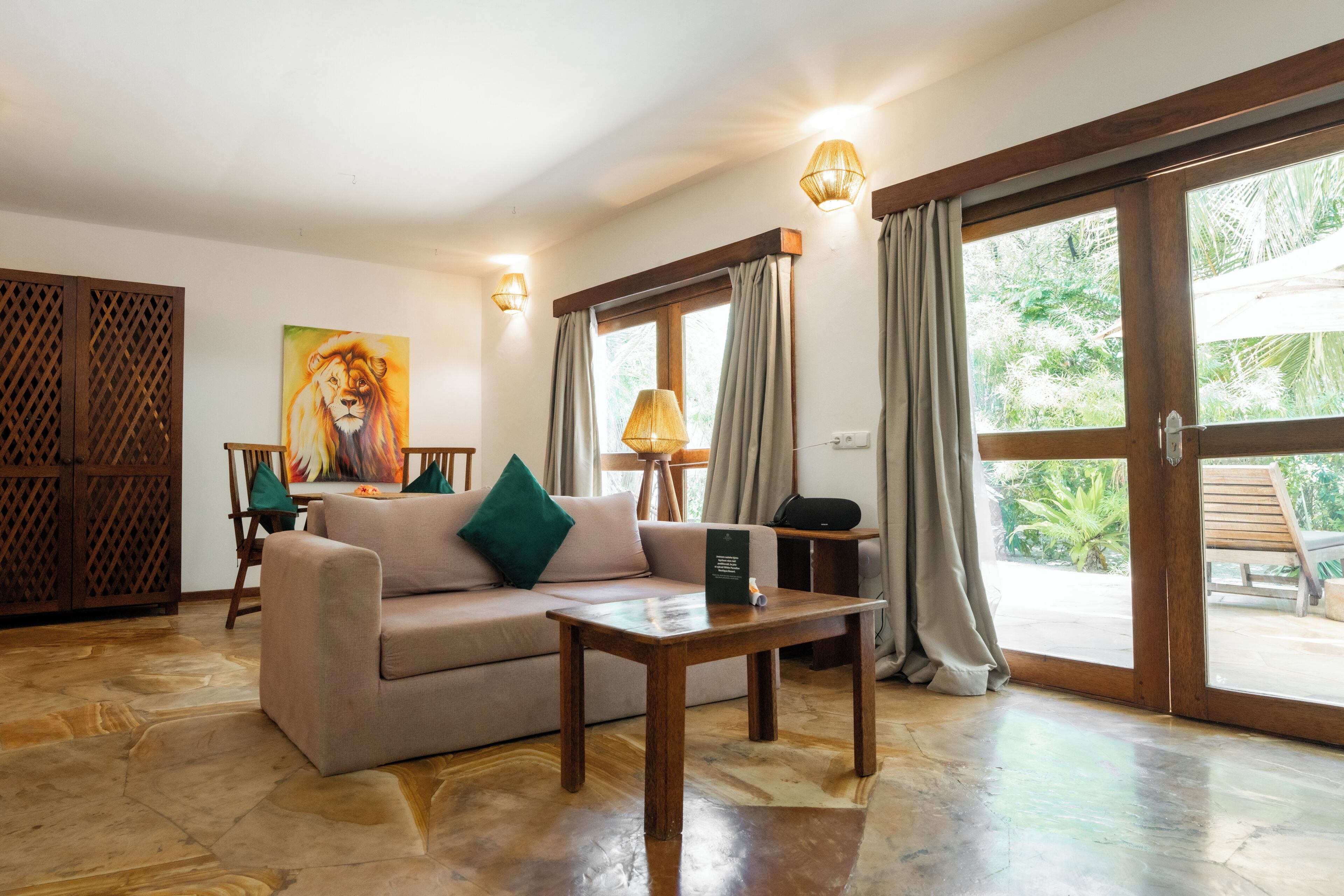 A room with a sofa, a table, a painting, and a view through a glass door.