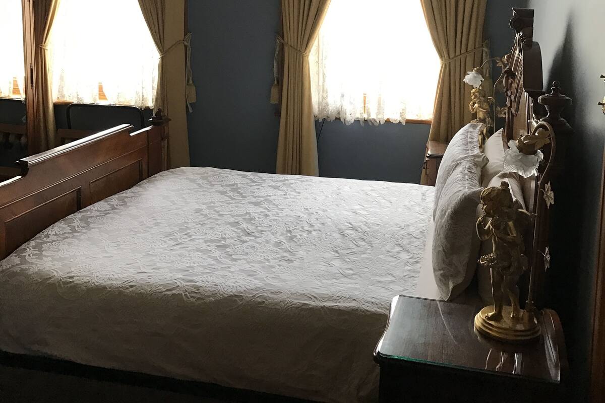 A bedroom with a large bed, ornate headboard, and a chandelier.