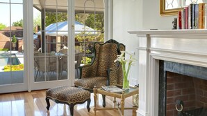 A room with a fireplace, a leopard-print sofa, a matching ottoman, and a glass coffee table with books and a vase. - Freeman On Ford (Beechworth)