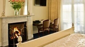 A hotel room with a fireplace, a bed, a desk, and a television. - Freeman On Ford (Beechworth)