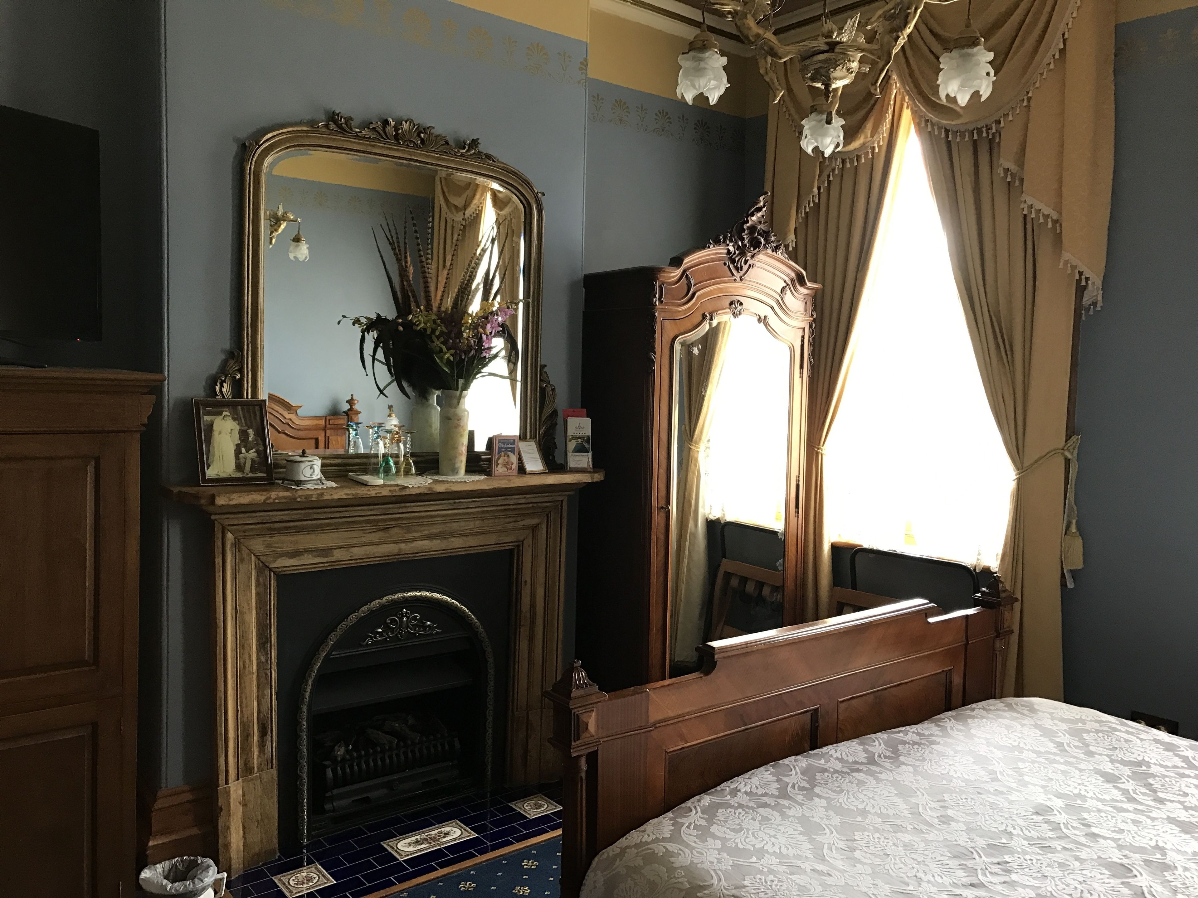 A bedroom with a fireplace, a large mirror, and a bed.