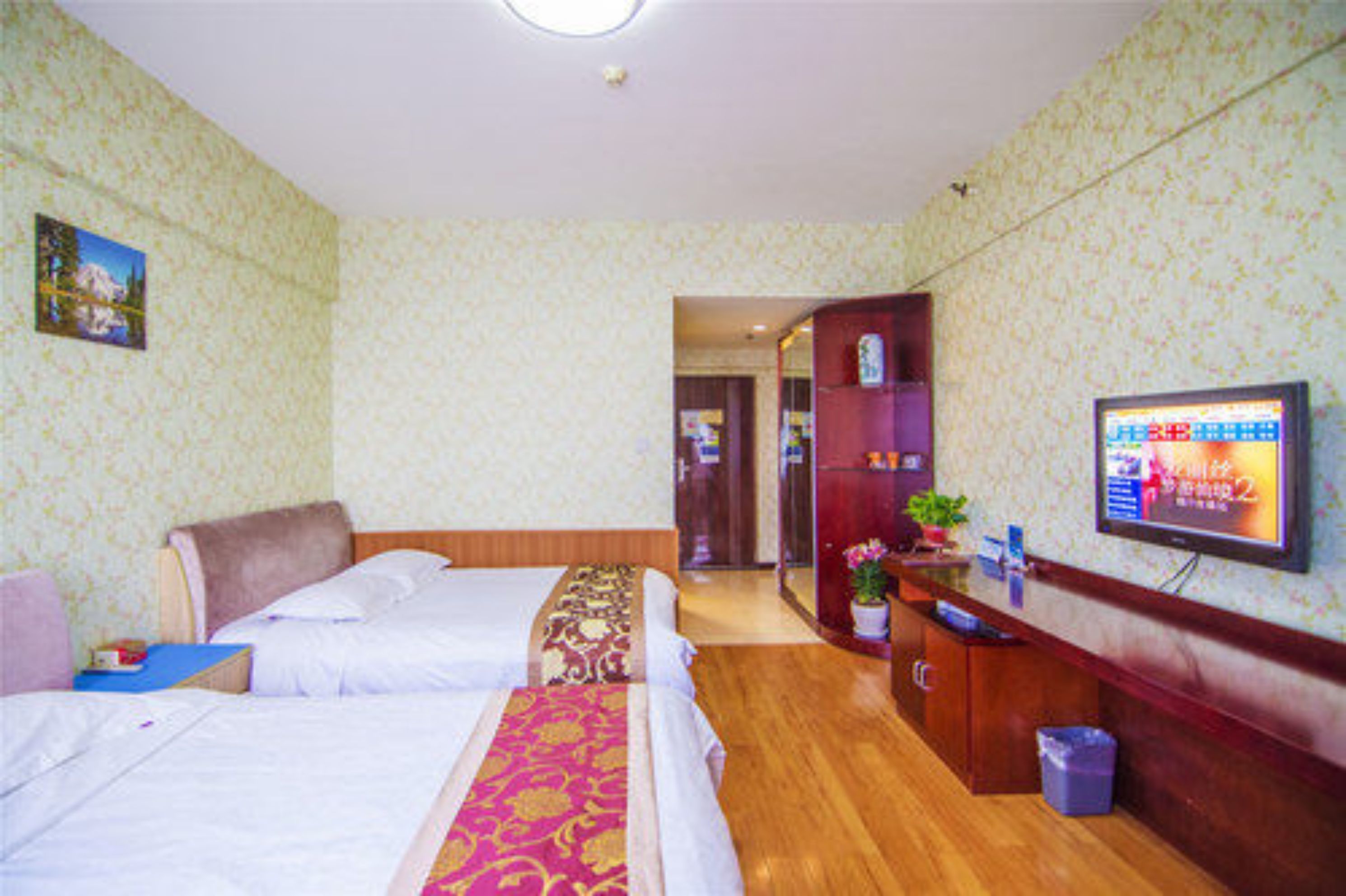 A hotel room with two beds, a TV, a desk, and a mirror.