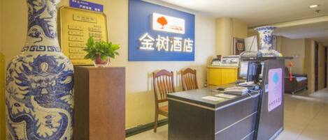 A reception desk with a sign reading "金树酒店" (Jinshui Hotel), a large blue and white vase, and a potted plant.