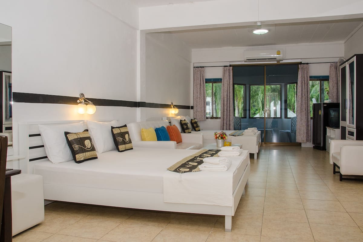 A hotel room with a large bed, a sofa, a TV, and a desk.
