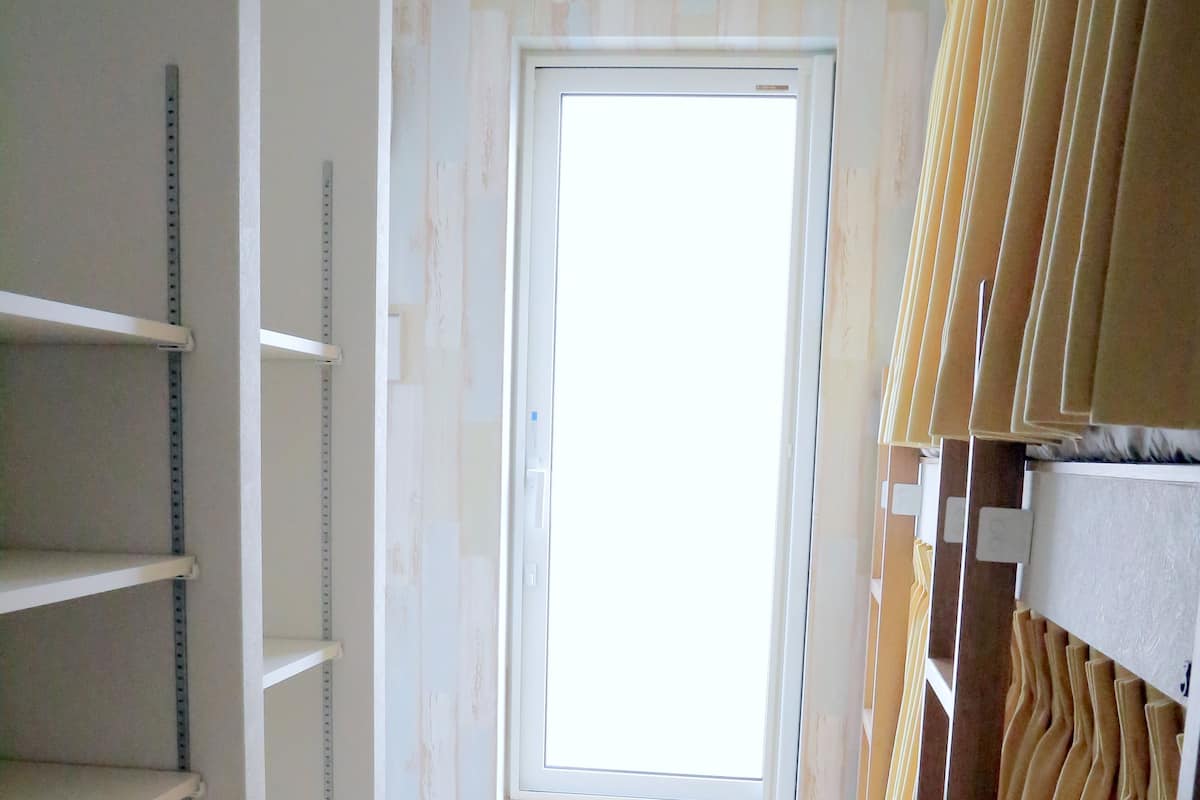 A room with a window, wooden floor, and shelves with measuring tapes.