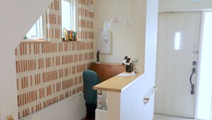A small office space with a desk, chair, and a radiator. There is a door with a handle and a window with blinds. - OCHO Guest House - Hostel (Sapporo)