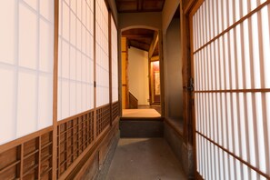 A traditional Japanese interior with sliding doors and a wooden staircase leading to a room.