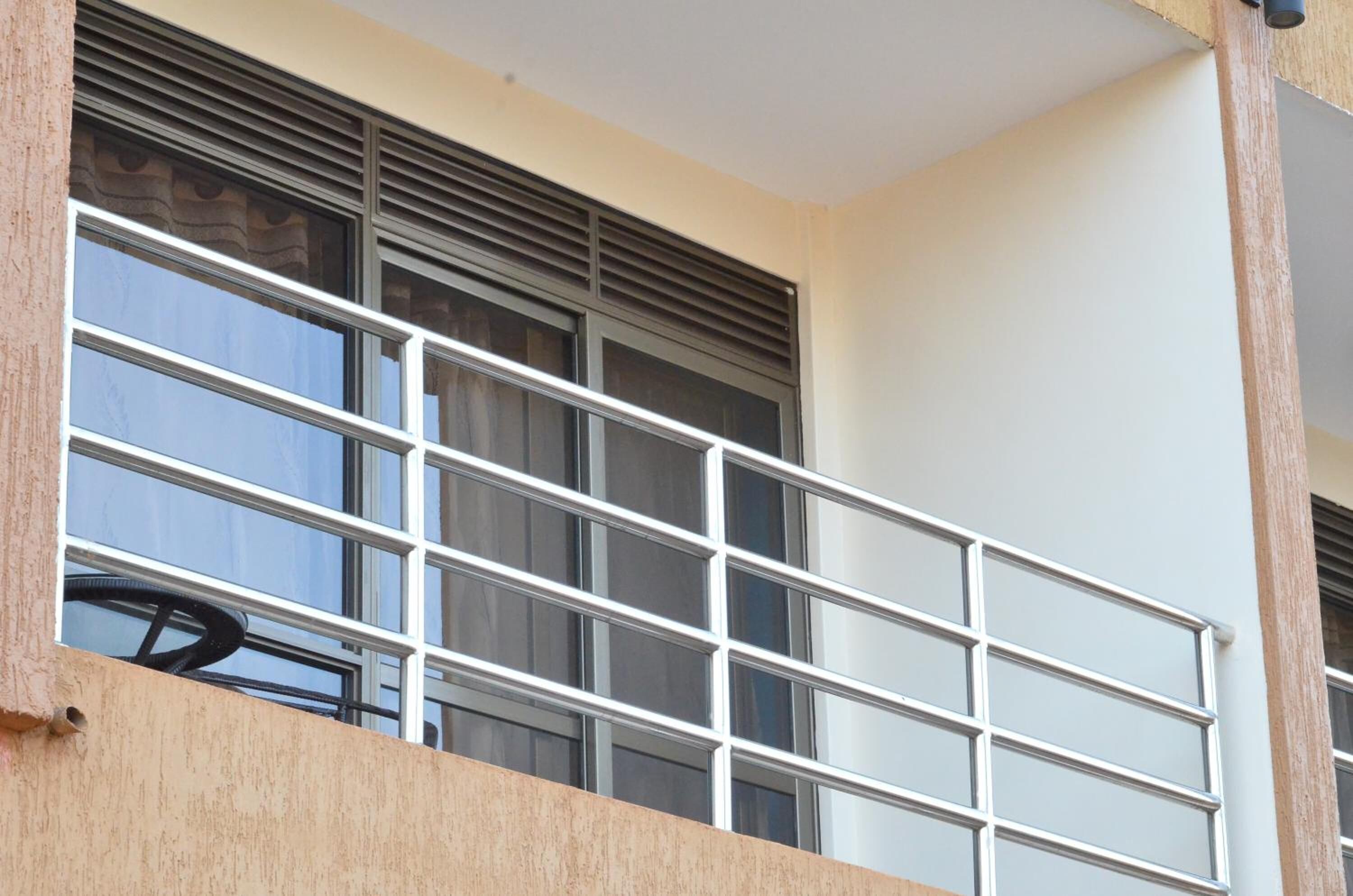A balcony with a metal railing and a window with blinds.