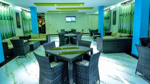 A modern indoor seating area with wicker furniture and a flat-screen TV mounted on the wall. - Interservice Hotel (Kampala)