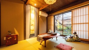 A traditional Japanese room with tatami flooring, a low wooden table, a red cabinet, and a view through shoji screens. - KumoMachiya Takasegawa (Kyoto)