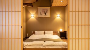 A neatly made bed with white linens, two bedside lamps, and a framed artwork on the wall. - KumoMachiya Takasegawa (Kyoto)