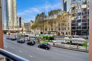 Una calle urbana con edificios modernos, un tranvía y automóviles.