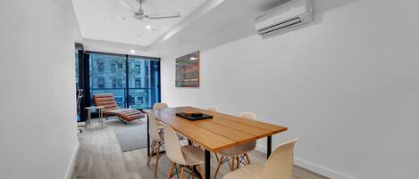 A modern dining area with a wooden table, six chairs, and a ceiling fan.