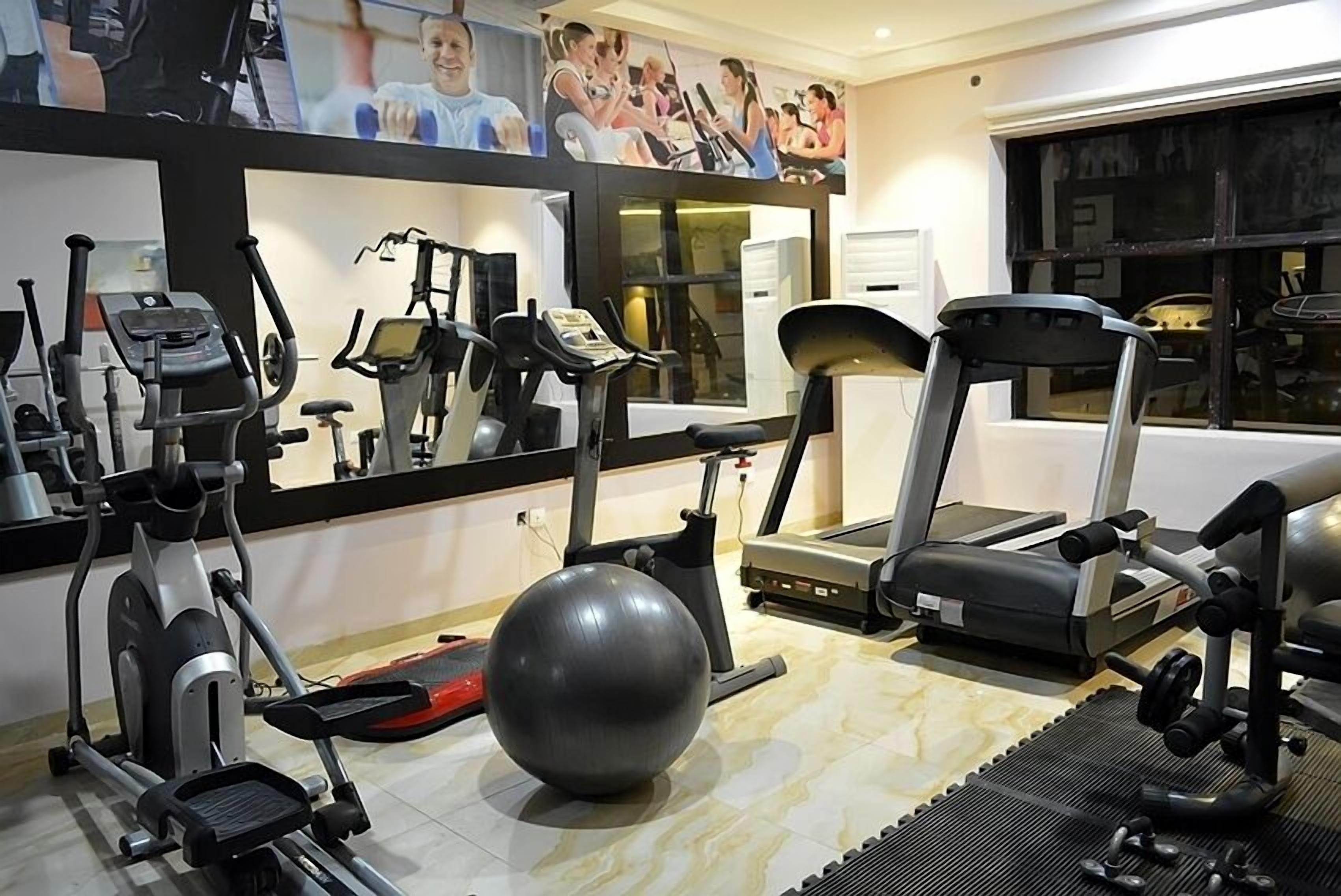 A gym with various exercise equipment, including treadmills, an elliptical, and a stationary bike.