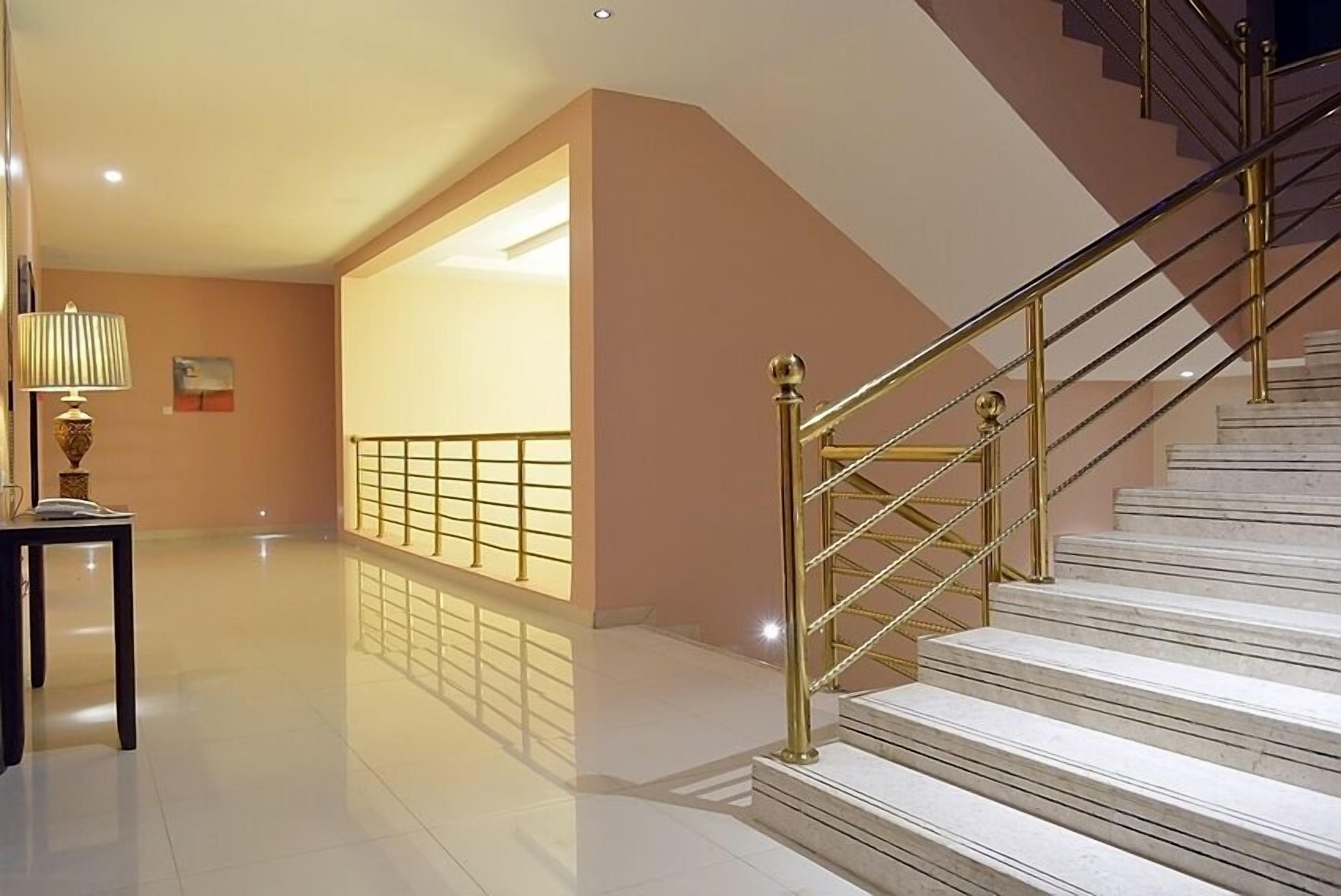 Un interior moderno con una escalera, un suelo pulido y una lámpara.