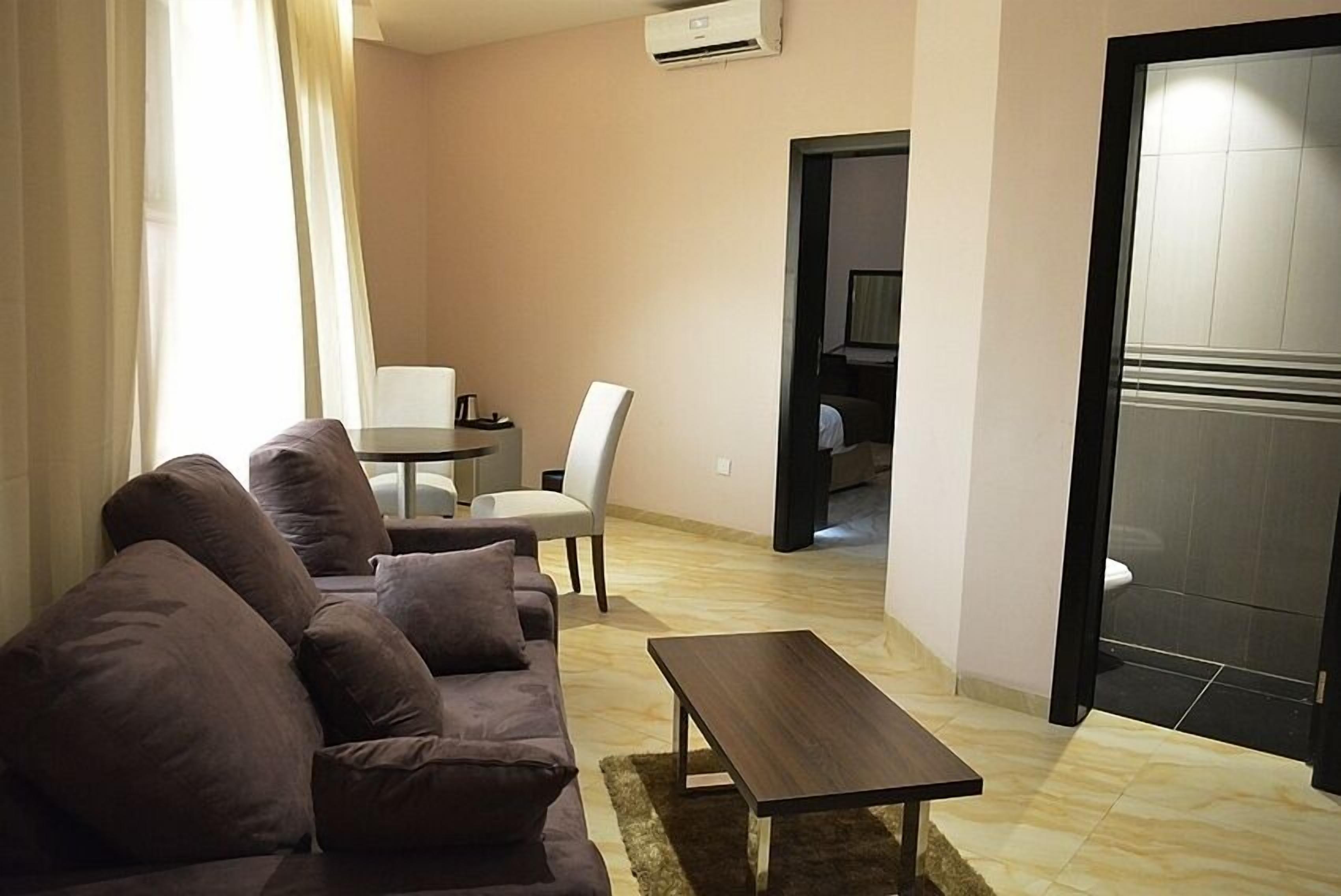 A modern living room with a sofa, a coffee table, and a dining area with a table and chairs.