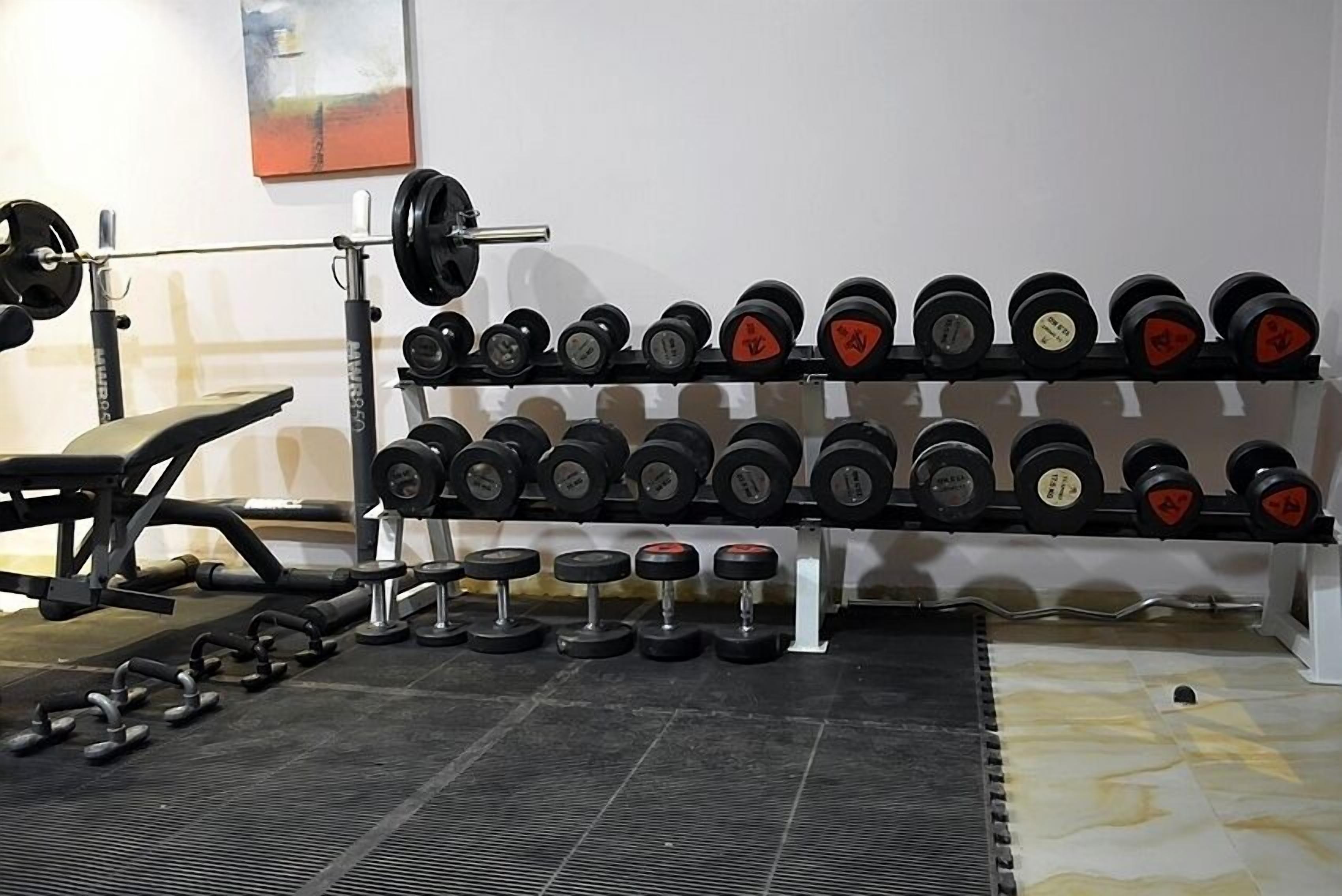 A gym with weightlifting equipment, including dumbbells and a barbell.