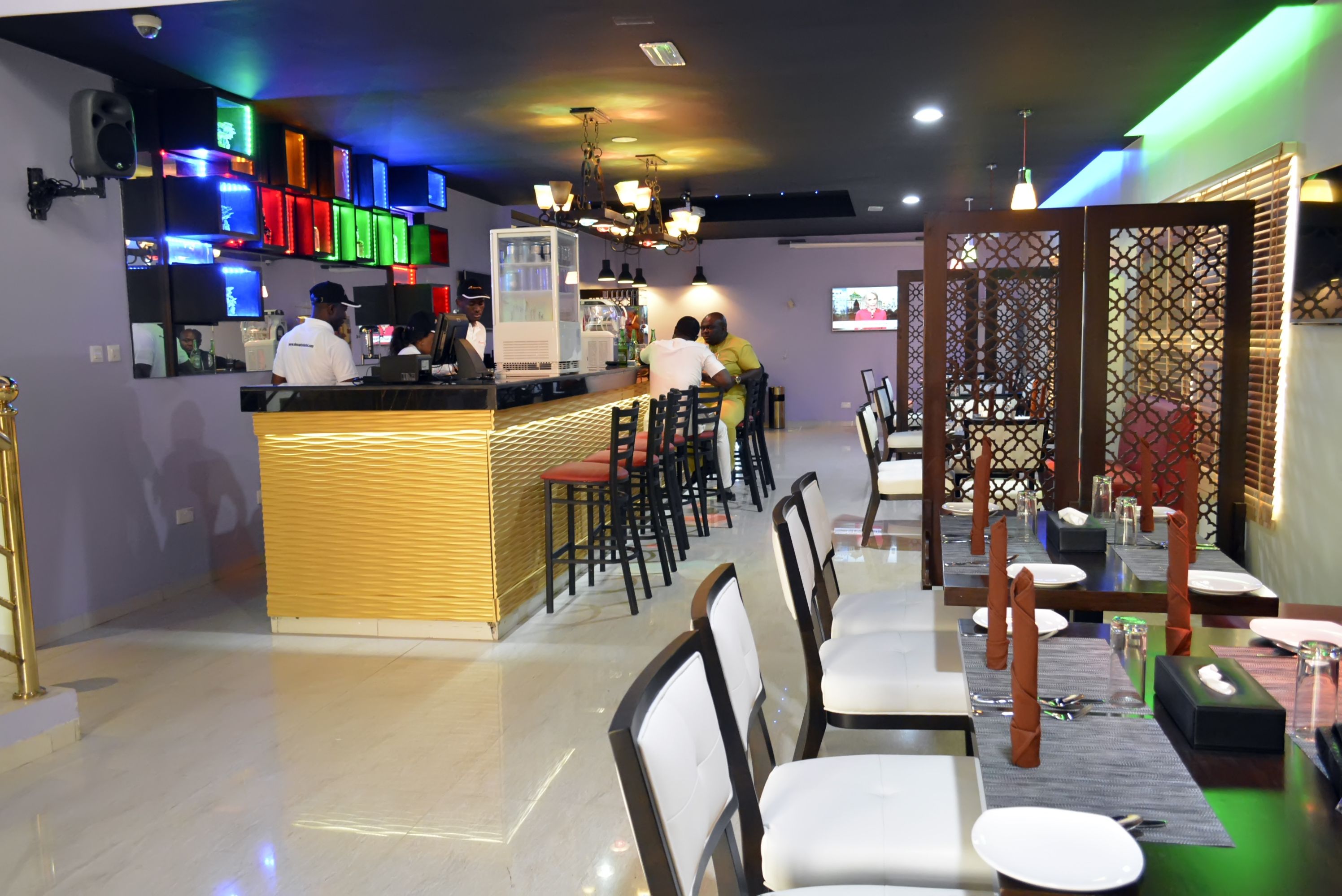 A restaurant with a bar area, multiple seating options, and a modern interior design.