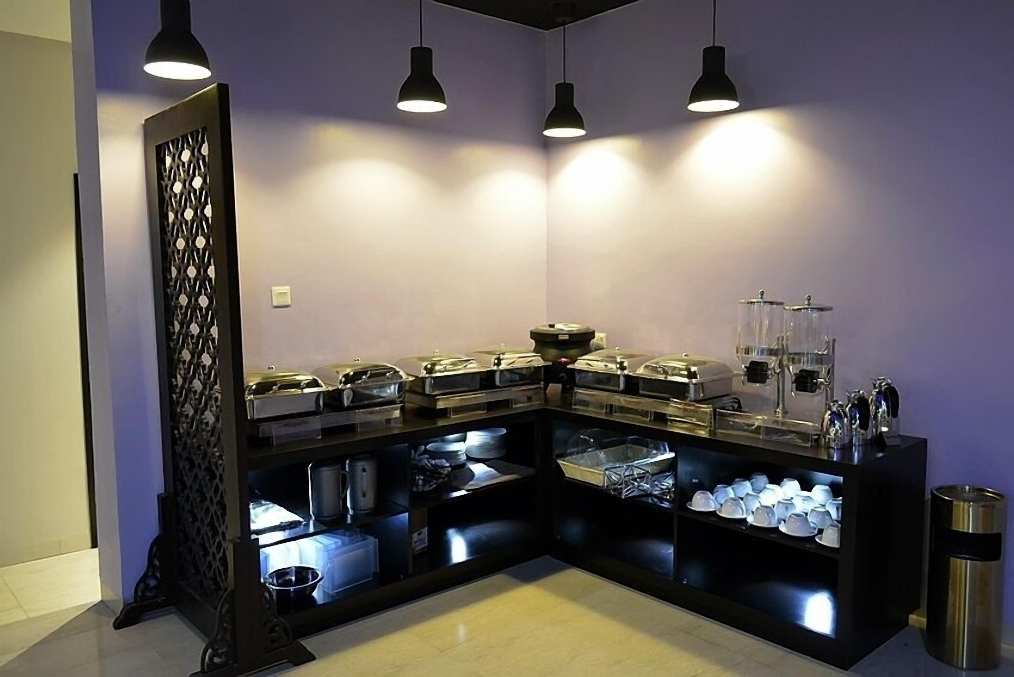 A buffet setup with various food containers and utensils, a decorative partition, and overhead lighting.