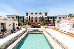 A pool area with a clear pool, steps leading to a building entrance, and outdoor seating. - Antmare Hotel (Cesme)
