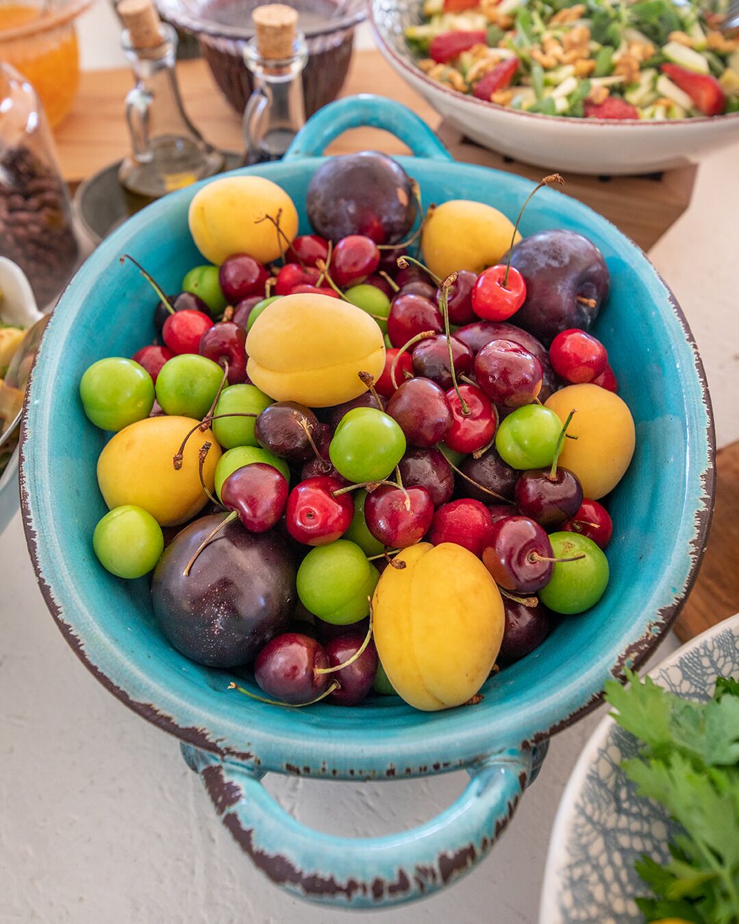 A bowl filled with various fruits including cherries, plums, and grapes.