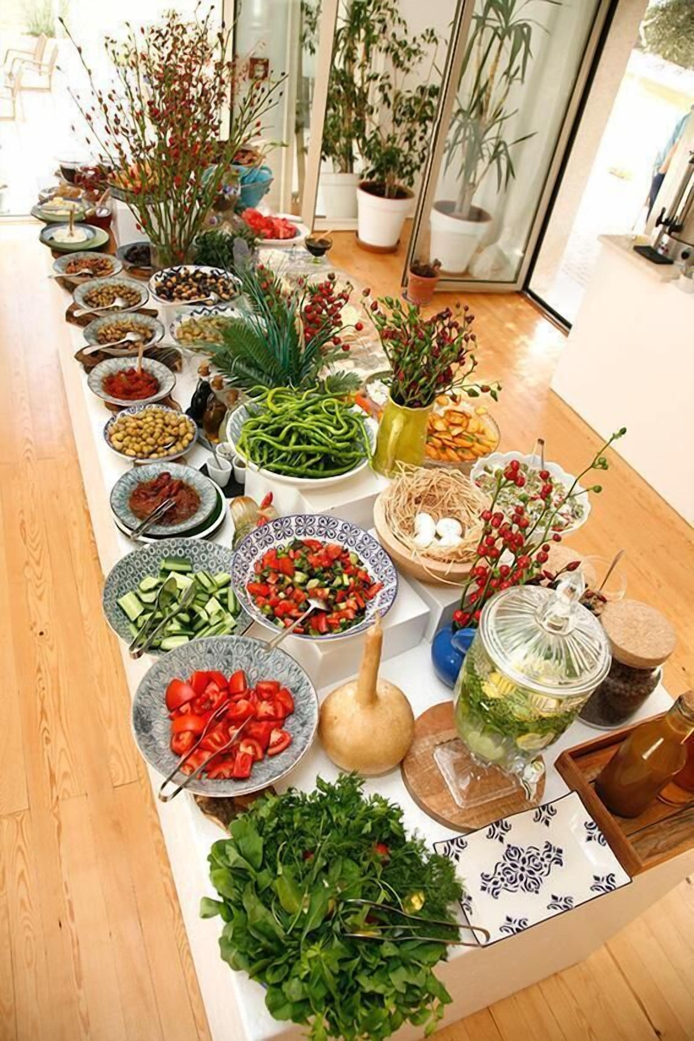 A buffet table with various dishes and fresh vegetables.
