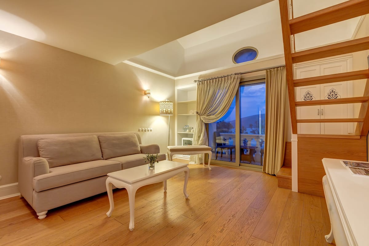 A living room with a sofa, coffee table, and a view of the outdoors through a large window.