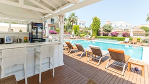 Un espace aménagé au bord de la piscine, avec des chaises longues, un bar et une piscine.